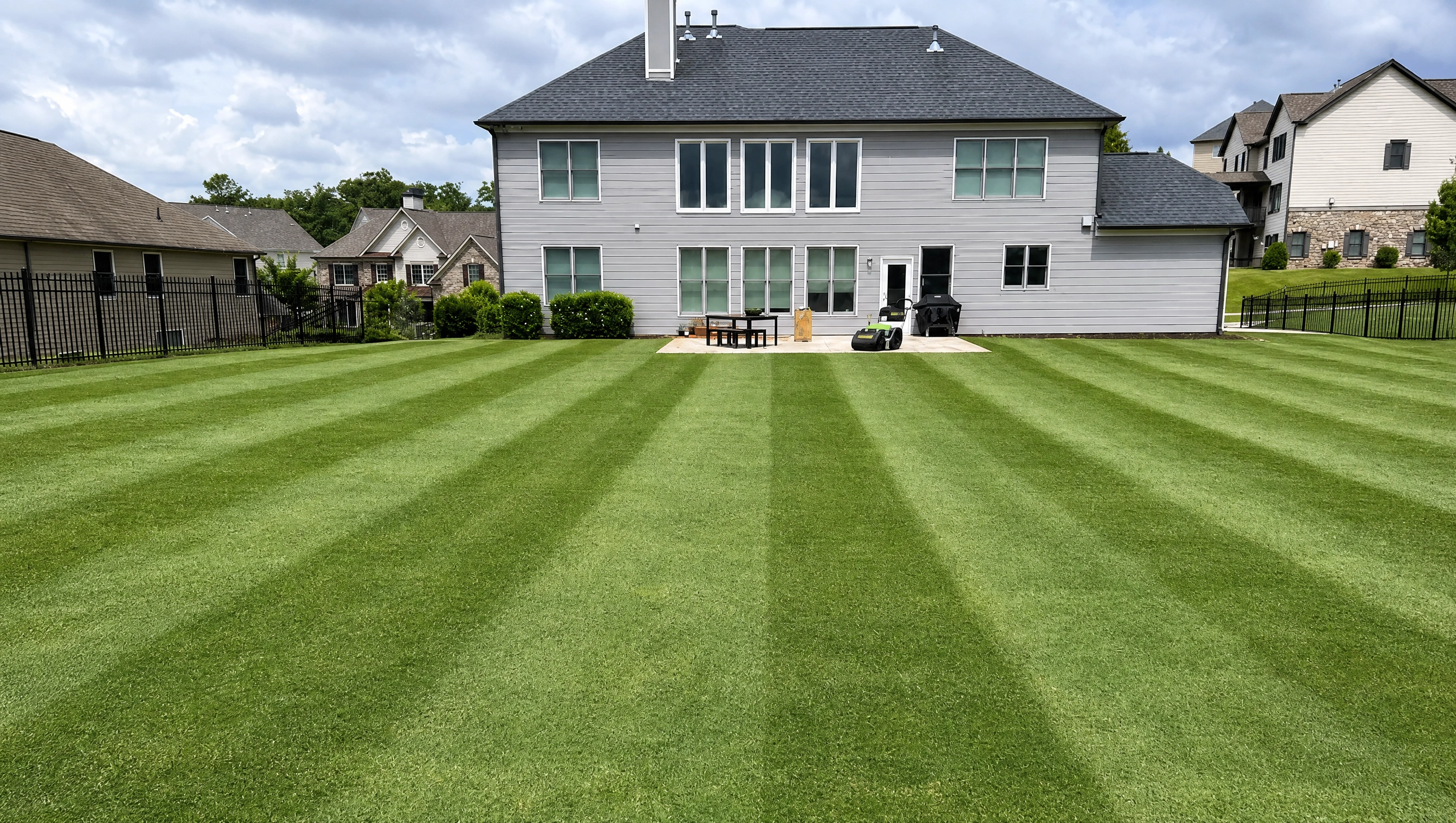 professional lawn mowing with fresh striped backyard grass behind residential home